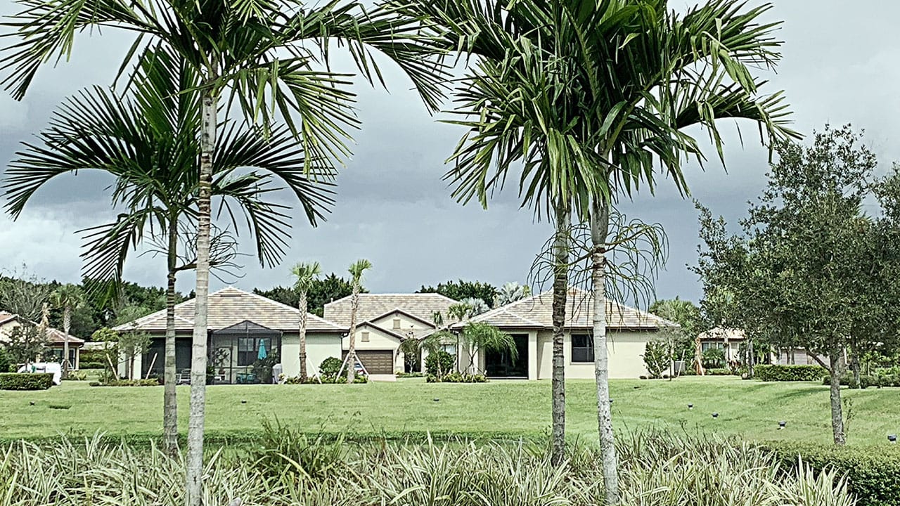 Houses on the Castellina estate with green grass and palm trees around them