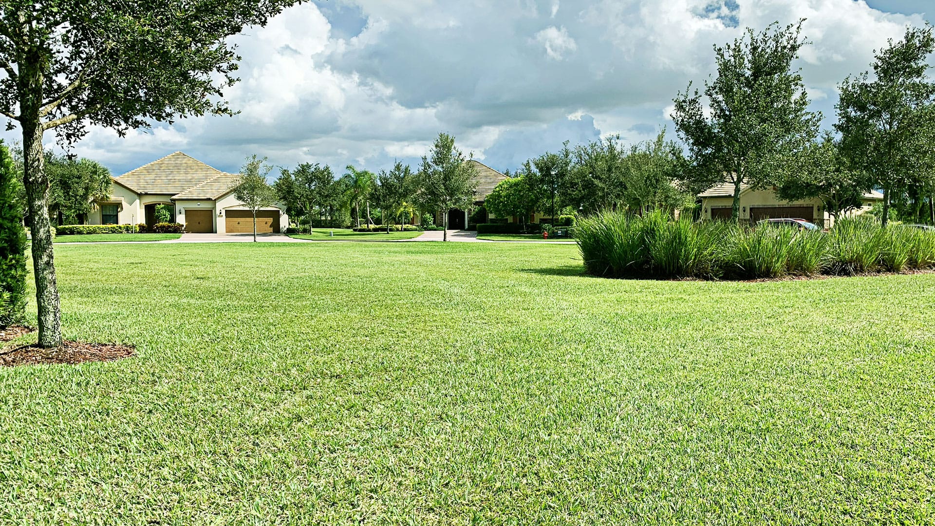 Green grass lawn in a gated community with trees in the distance