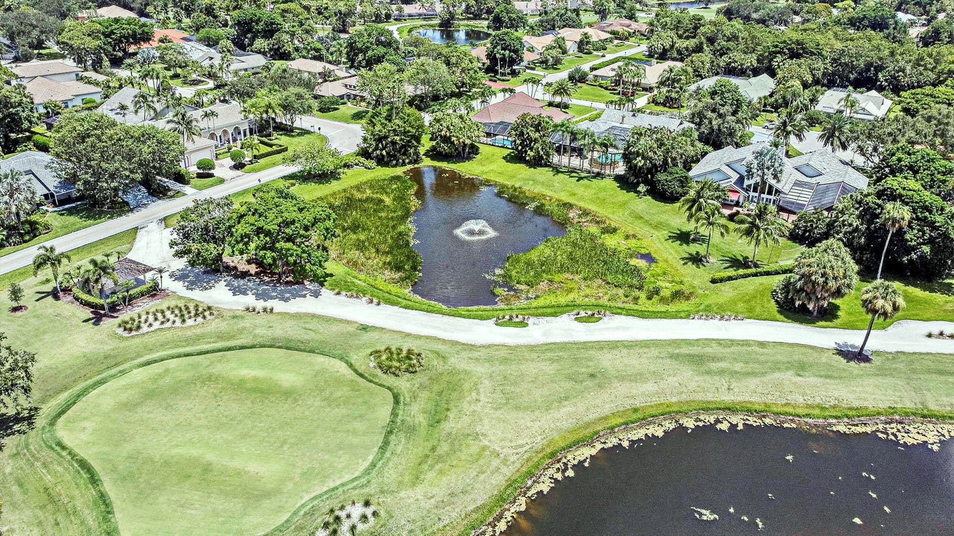 PGA drone view of the pond surrounded by grass and housing