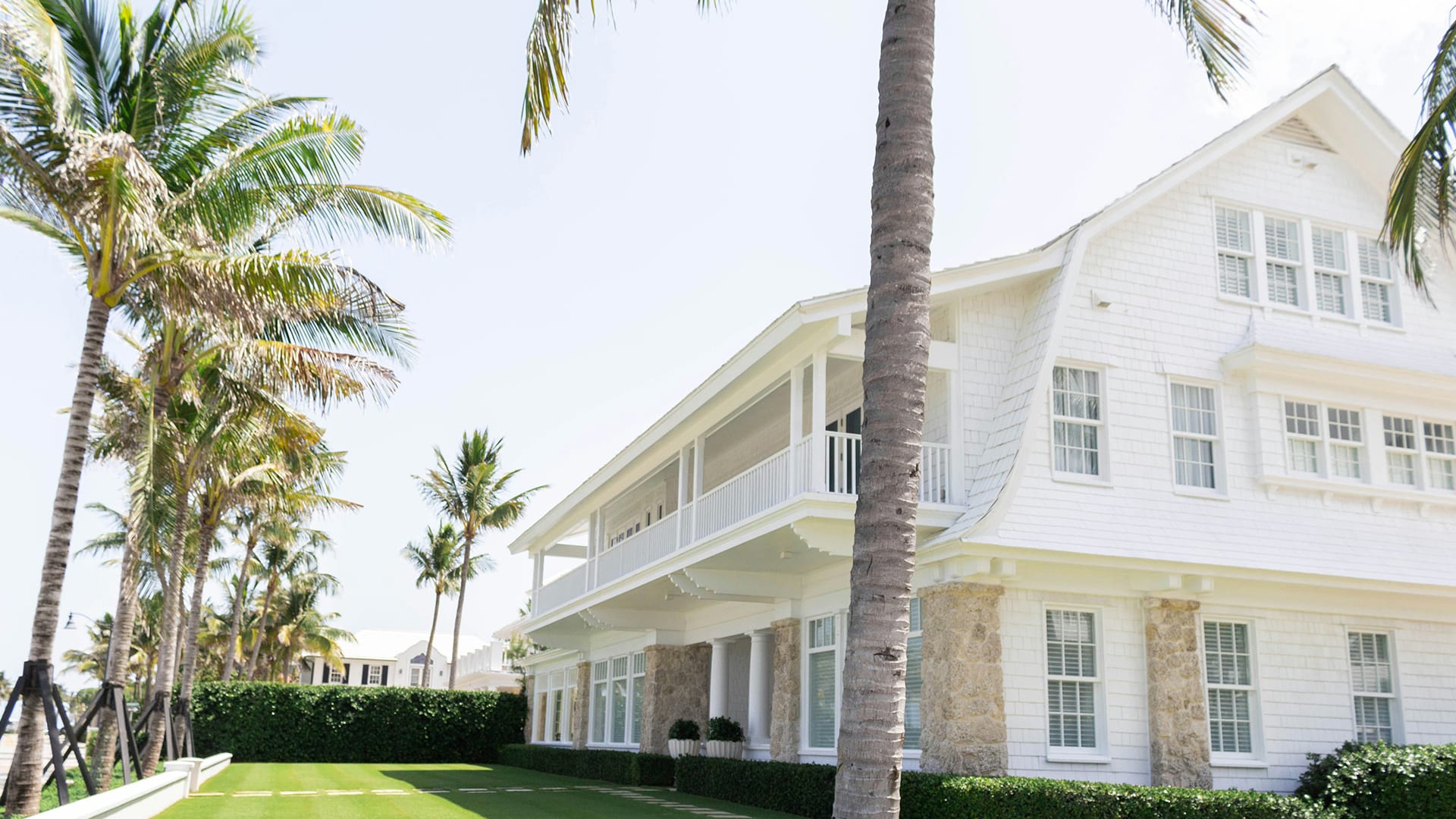 White house with green garden and palm trees