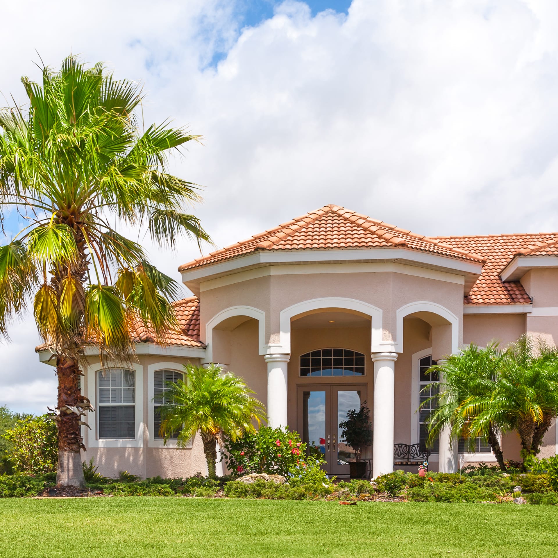 Front of a Florida mansion with palm trees outside