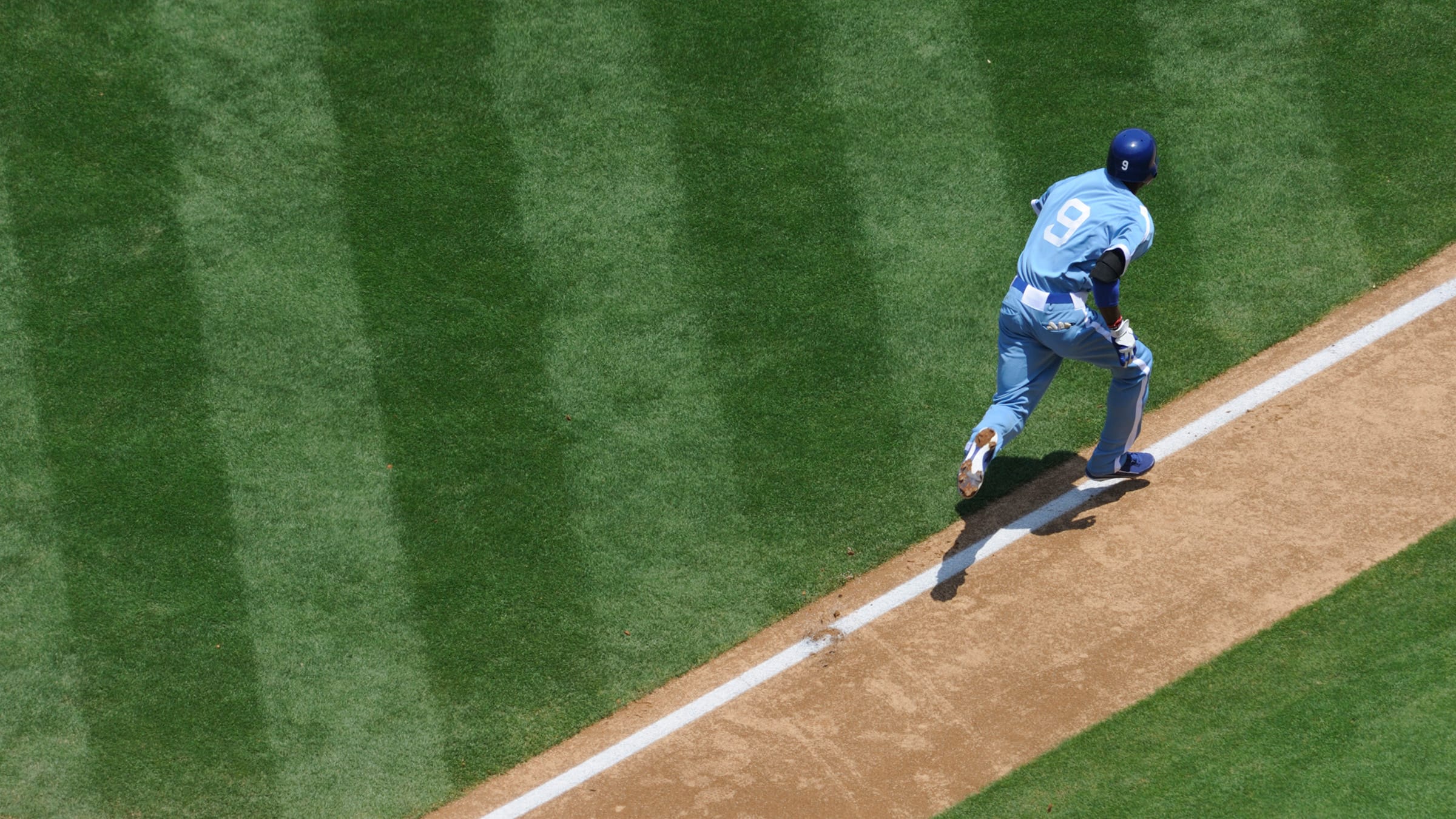 Close up of a baseball on the grass pitch with a player running