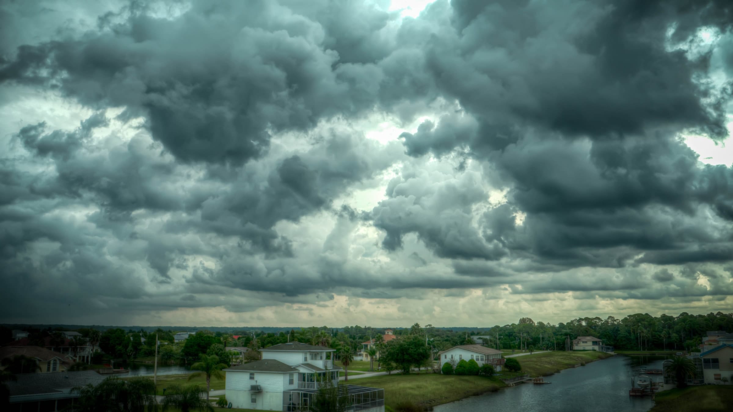 Looking over a housing estate from the water with lots of blue cloudy sky above