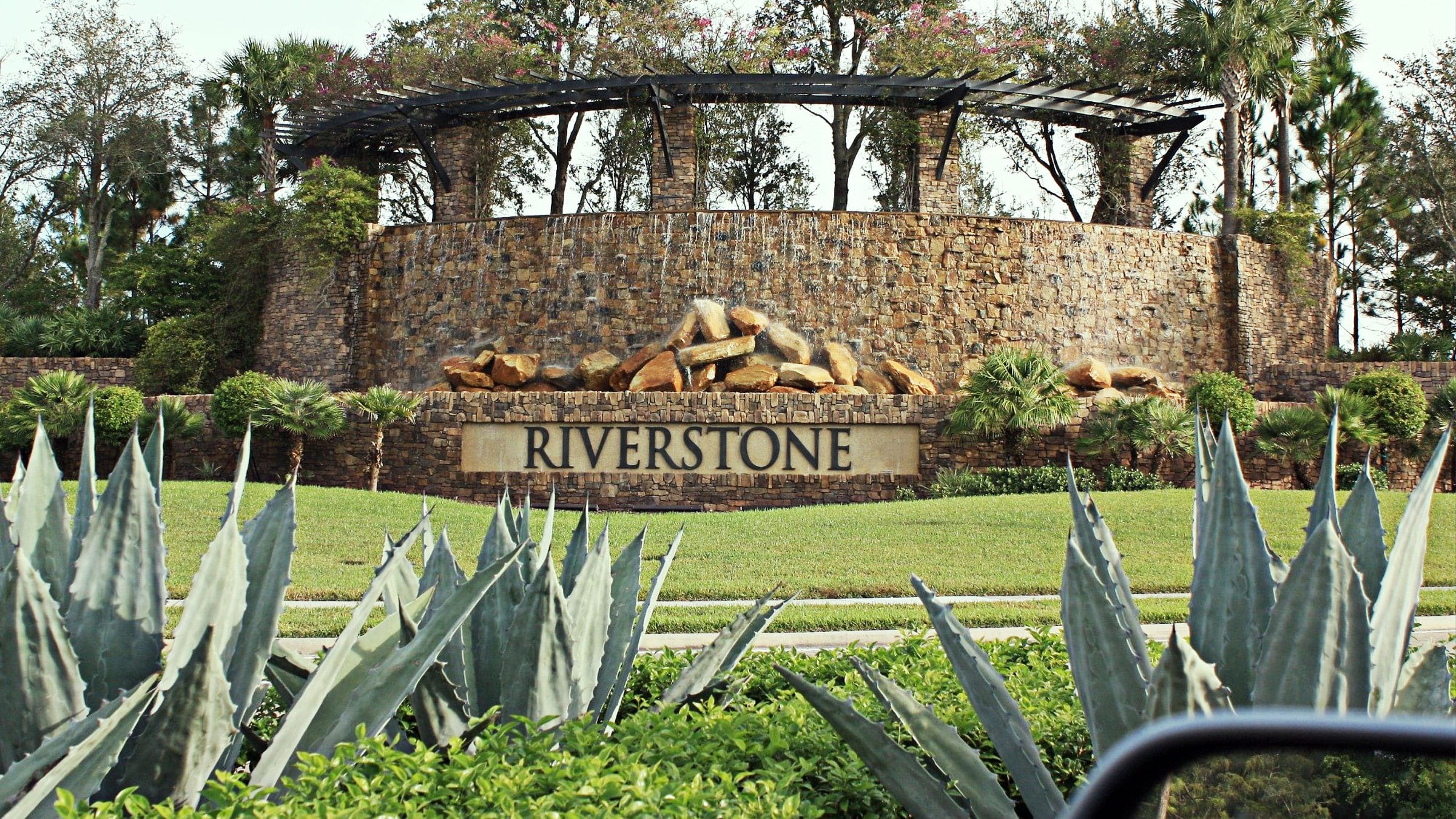 Riverstone entrance sign with grass and plants to the fore