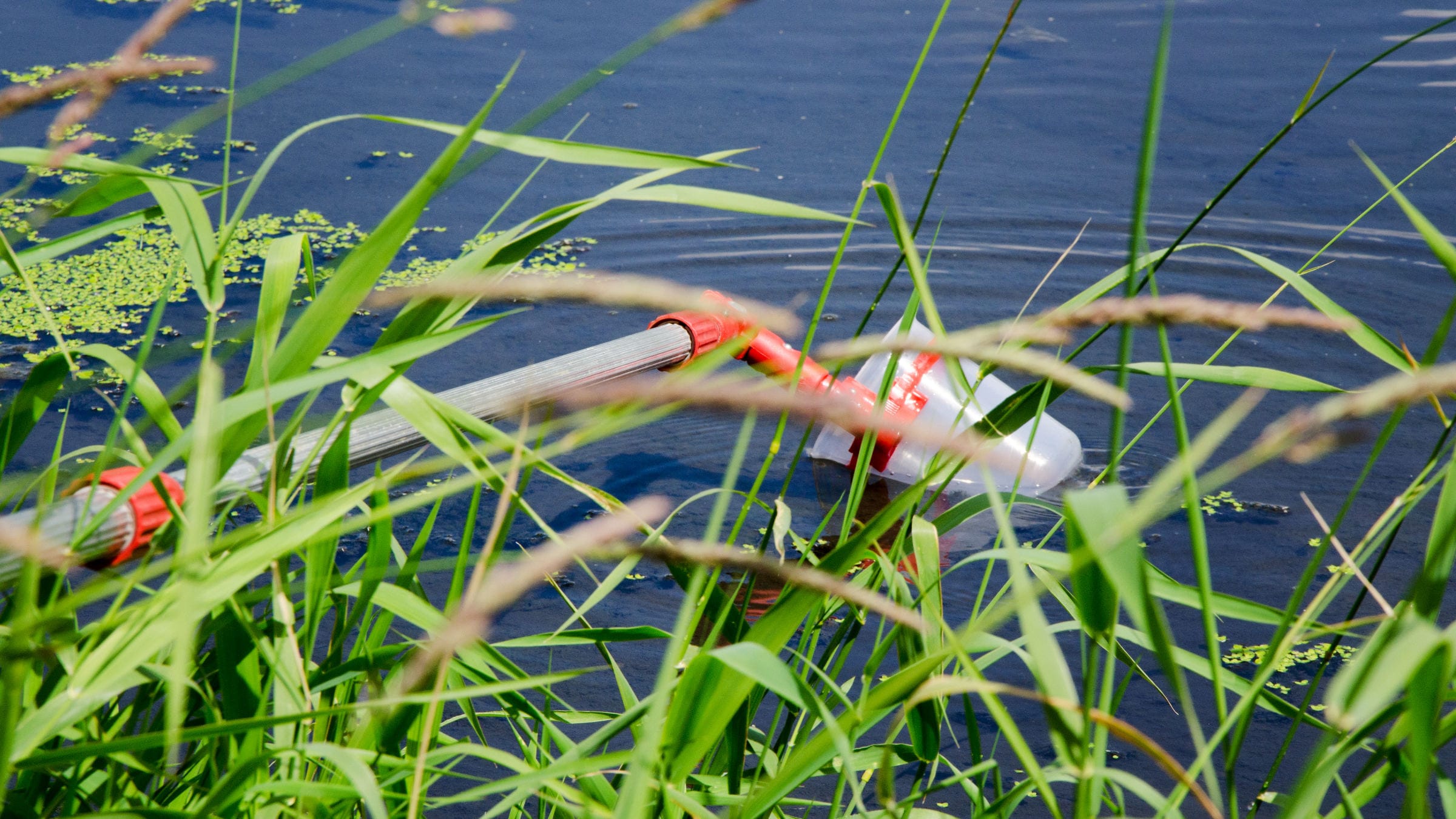A pole collecting water from a lake to make pH checks